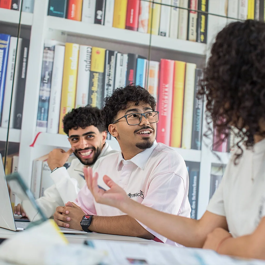Bibliothek: Lernende im Gespräch am Laptop