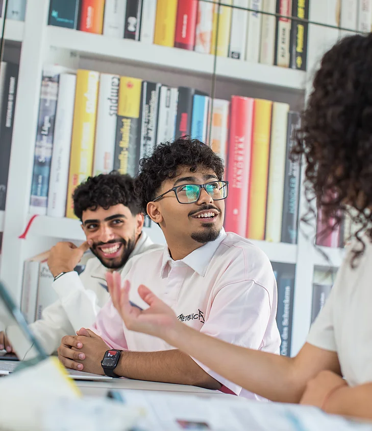 Bibliothek: Lernende im Gespräch am Laptop